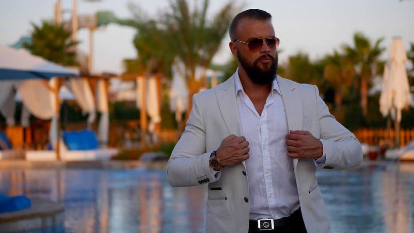 Kollegah vor einem Swimming Pool unter Palmen